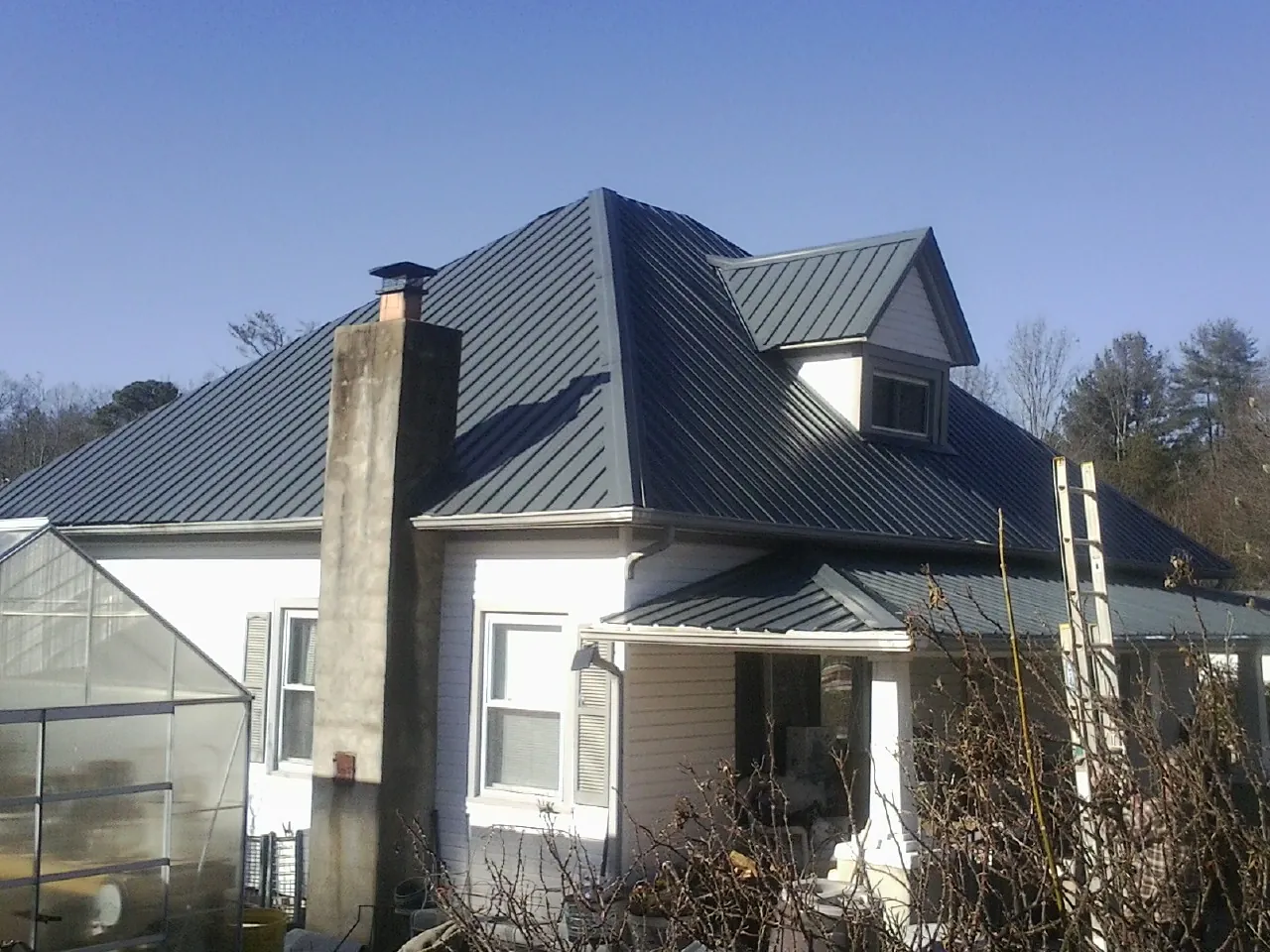 Dark blue standing seam metal roof on a white farmhouse with dormer — Slate & Tile Roof Repair by Roofing Brothers in Francitas