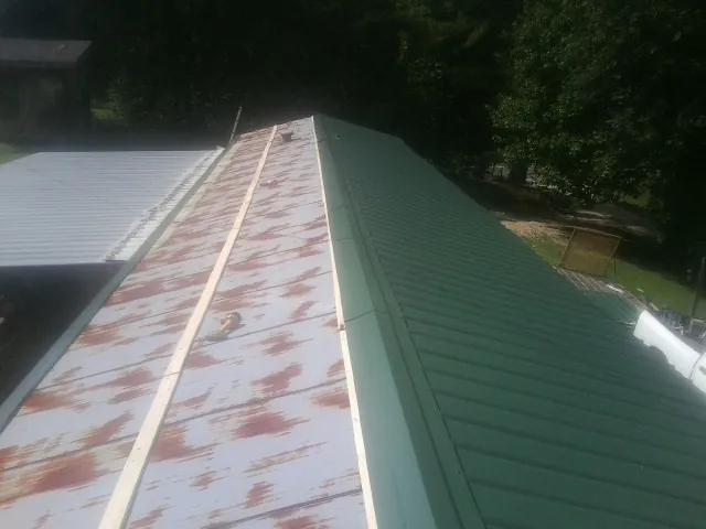 Old rusted panels beside newly installed green metal roofing — Wind Damage Roof Repair by Roofing Brothers in Francitas