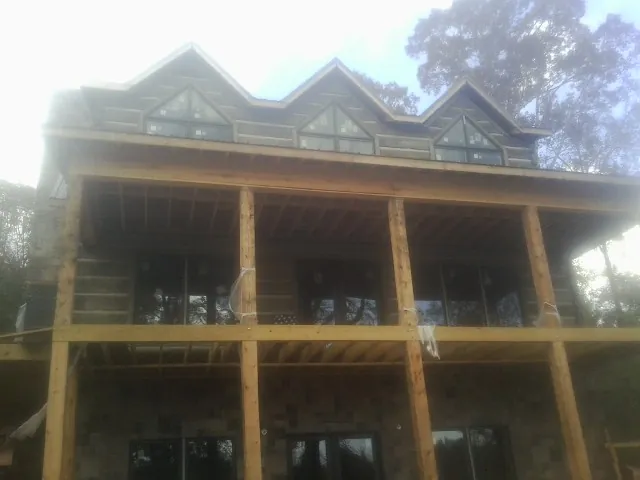 Dormers and porch framing on a large log home under construction — Roof Coating work by our crew in Francitas