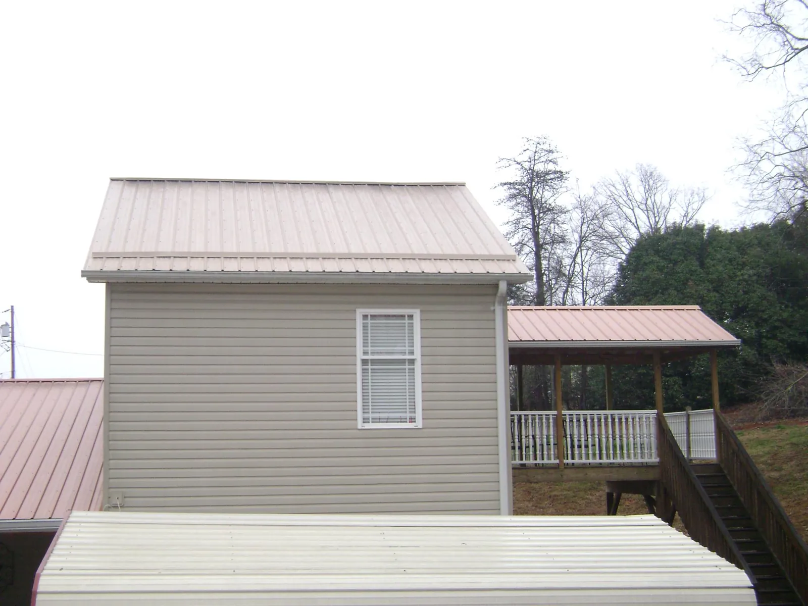 Tan metal roofs on a two story addition and attached porch, from a Roof Replacement job in Francitas