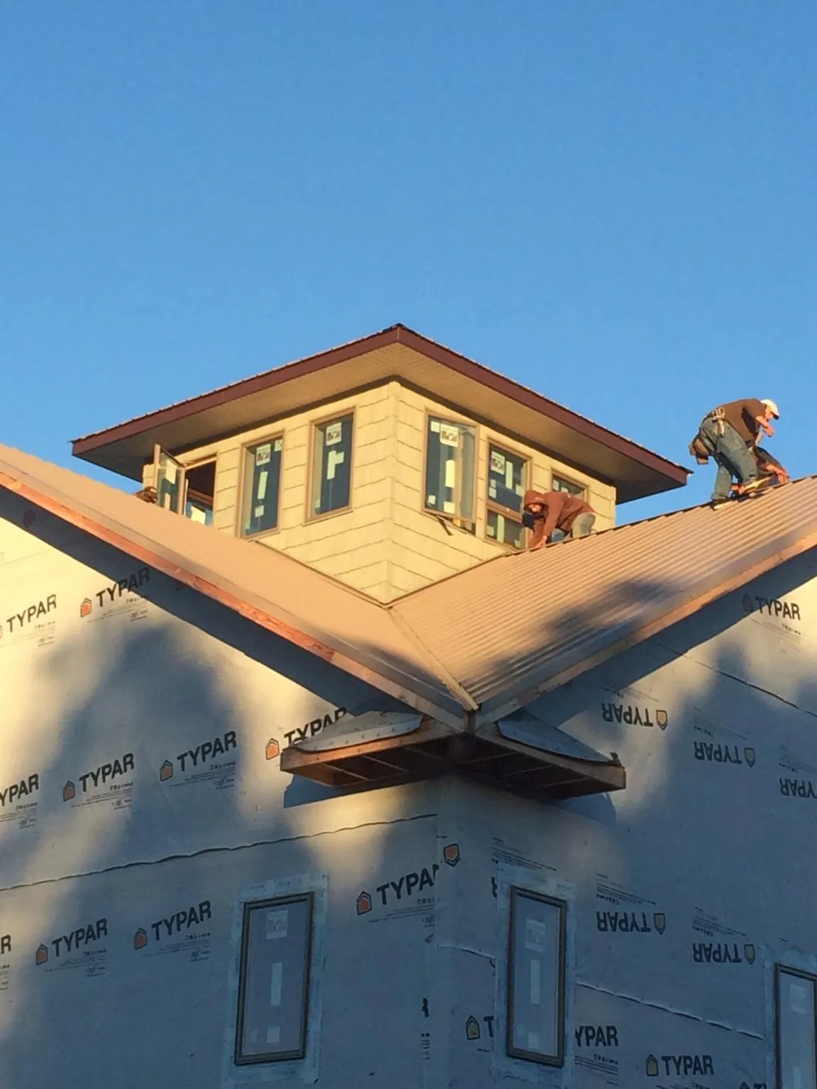Roofers working around a rooftop cupola on a new metal roof at sunset — Roof Waterproofing in Francitas by Roofing Brothers